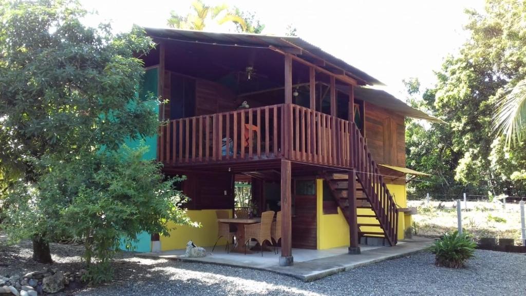 une maison en bois avec une terrasse et une table dans l'établissement Haus mit trop Garten am Cahuita Nationalpark, à Comadre