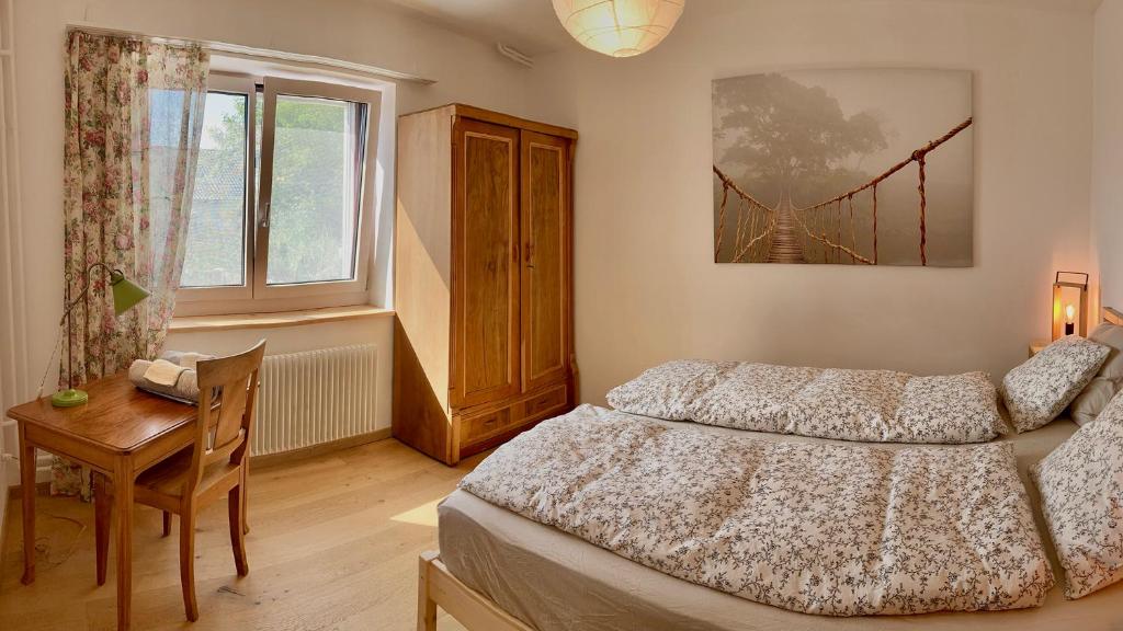 1 dormitorio con cama, escritorio y ventana en Le Gîte du Midi, en Fontainemelon