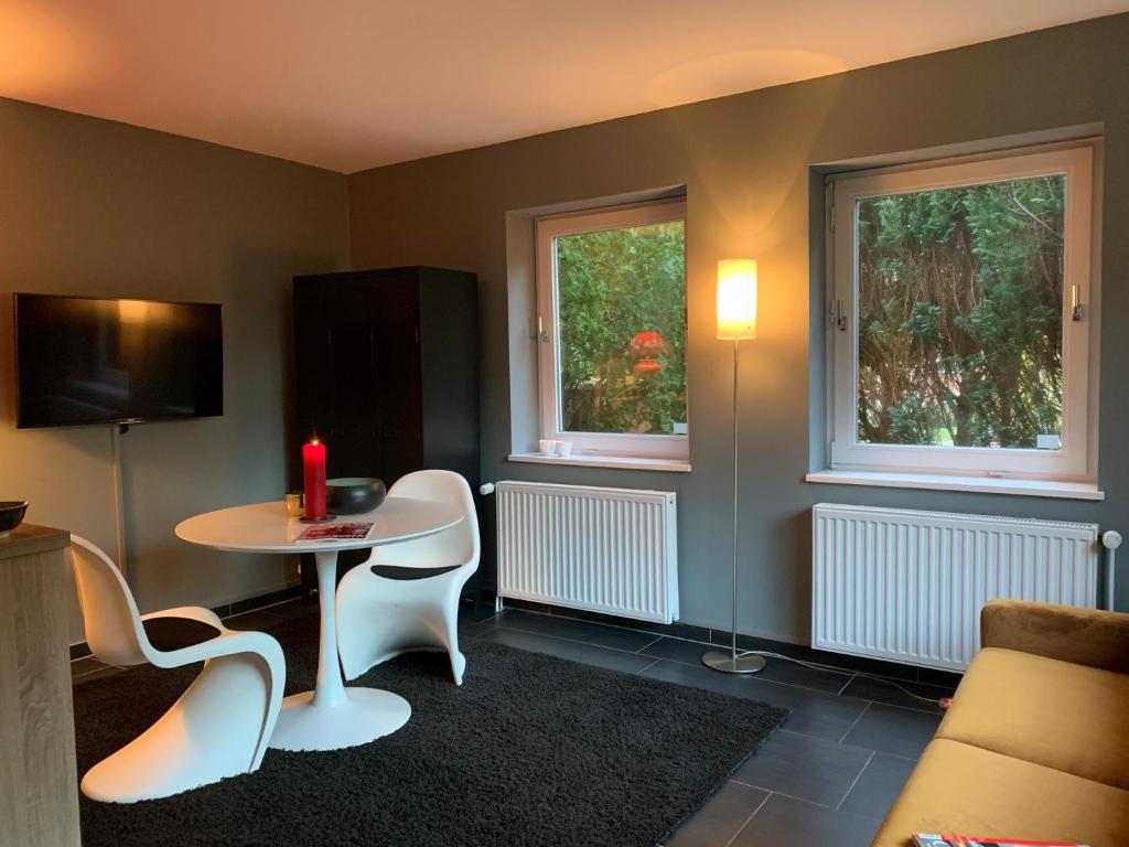 - un salon avec une table, des chaises et 2 fenêtres dans l'établissement Mini-Ferienhaus Petersberg, à Eckernförde