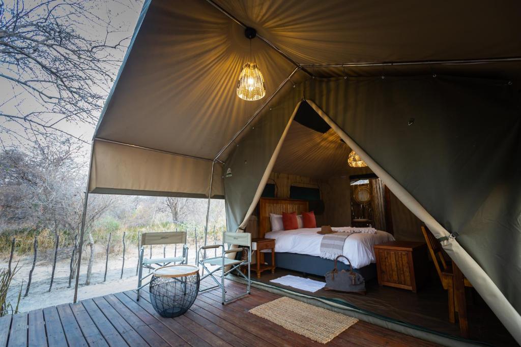 a large tent with a bed and a deck at Boteti Tented Safari Lodge in Maun
