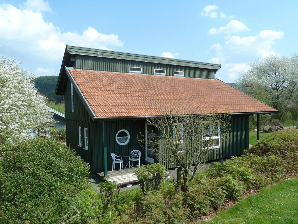 Cabaña verde con techo rojo en Ferienhaus Nr 8D, Feriendorf Hagbügerl, Bayr Wald, en Waldmünchen