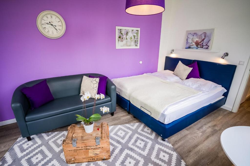 ein Schlafzimmer mit einem Bett, einem Sofa und einer Uhr in der Unterkunft Studio 11 "Blumenmeer" in Grömitz