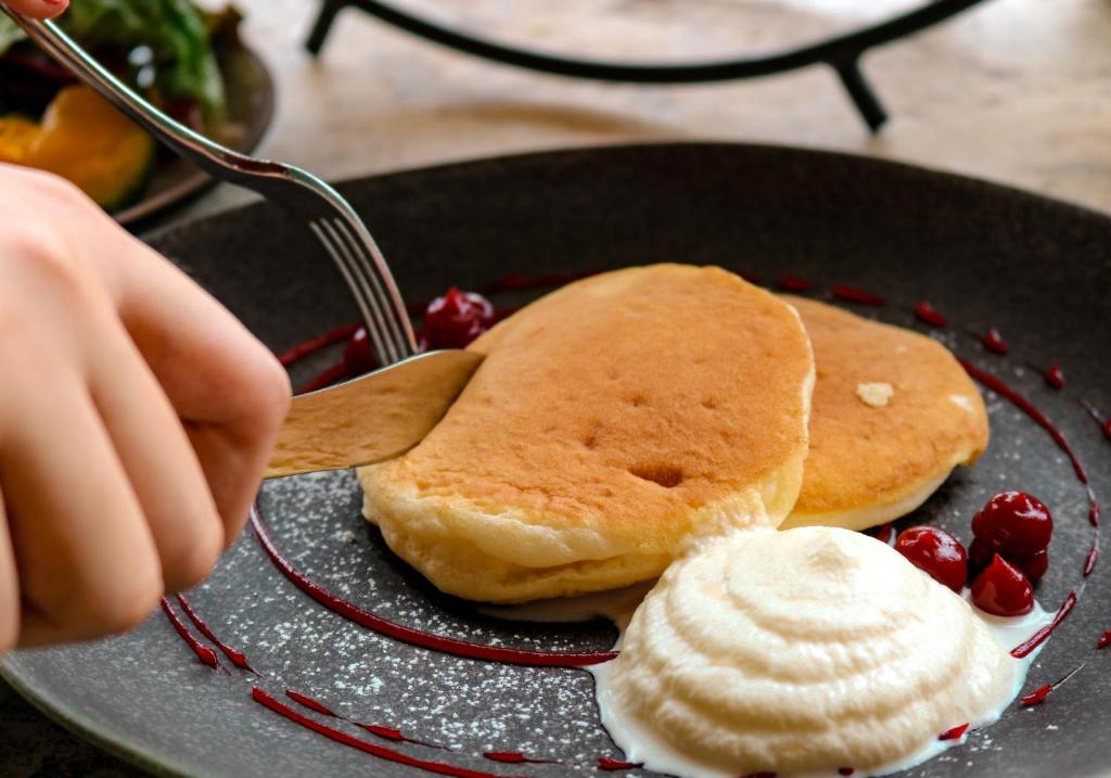 Pancakes served with whipped cream, berry sauce and fruit.