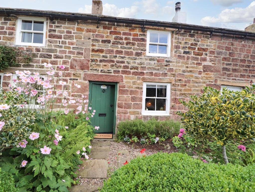 een stenen huis met een groene deur en bloemen bij Duckdown in Clitheroe