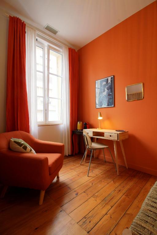 une chambre orange avec un bureau et une chaise dans l'établissement Maison d'hôtes Alma, à Bordeaux