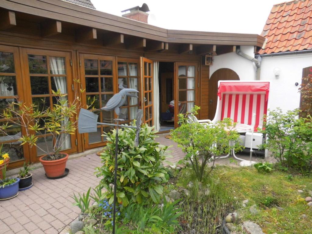 ein Haus mit einer Terrasse mit einem roten und weißen Stuhl in der Unterkunft Ferienwohnung zur Weide in Heiligenhafen