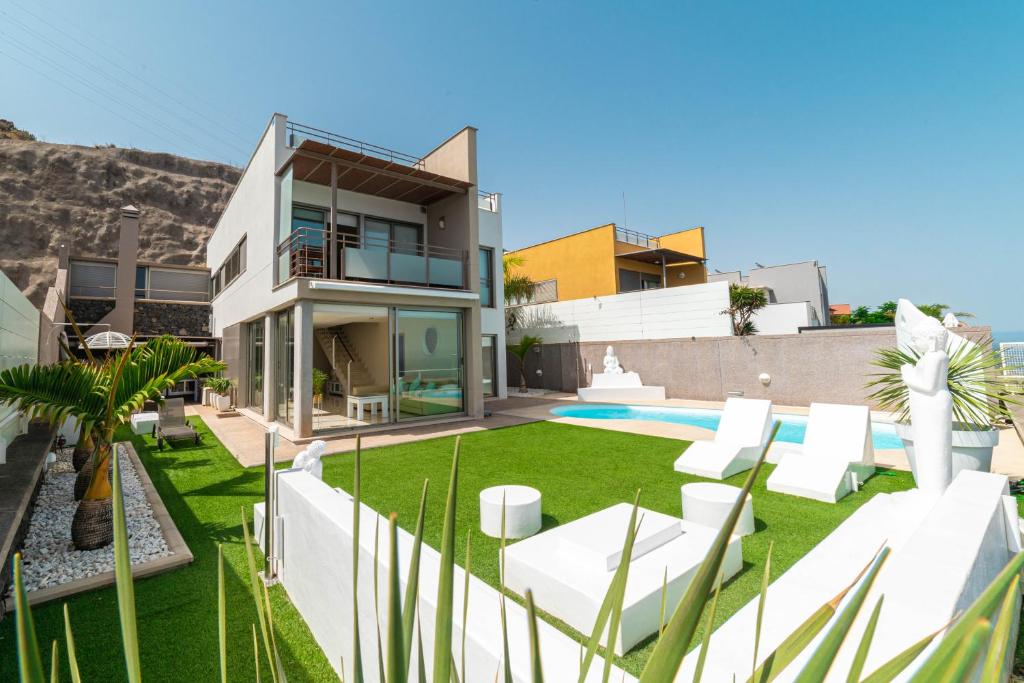 a house with a yard with white furniture and a pool at VILLA LUXURY VISTA DE MAR in Santa Cruz de Tenerife