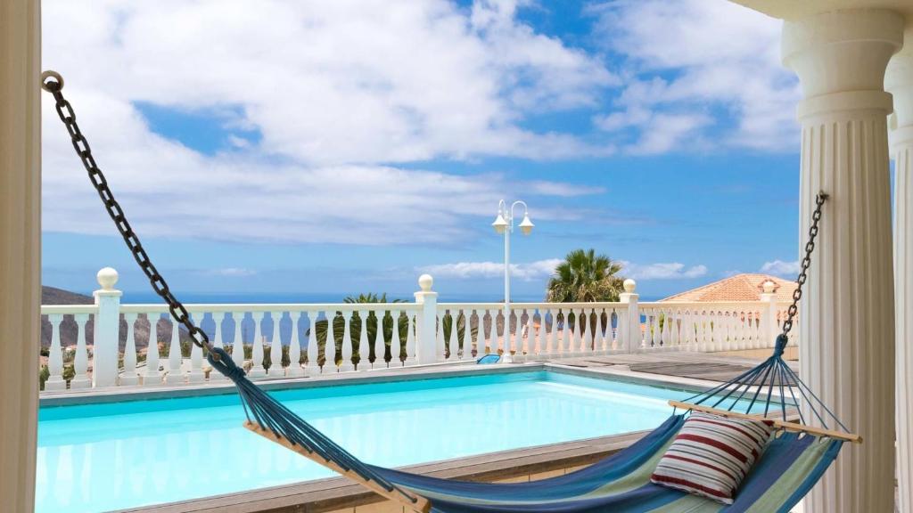 a hammock on a porch with a swimming pool at Penthouse Vistamar in Chayofa