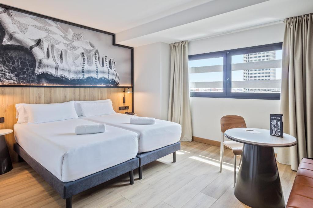 a hotel room with a bed, chair, table and a tv at Andante Hotel in Barcelona