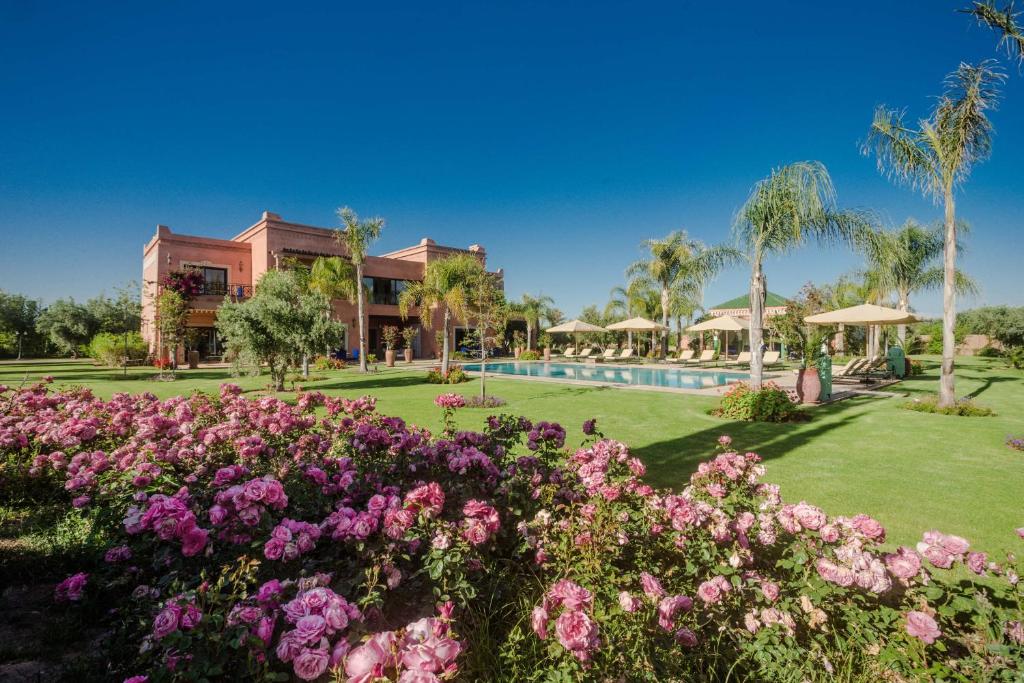 a garden with pink flowers in front of a building at La Villa Rose Anna in Marrakesh