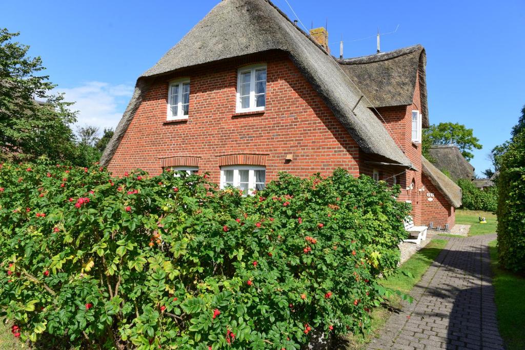 uma grande casa de tijolos vermelhos com telhado de palha em Drei Krabben em Süderende
