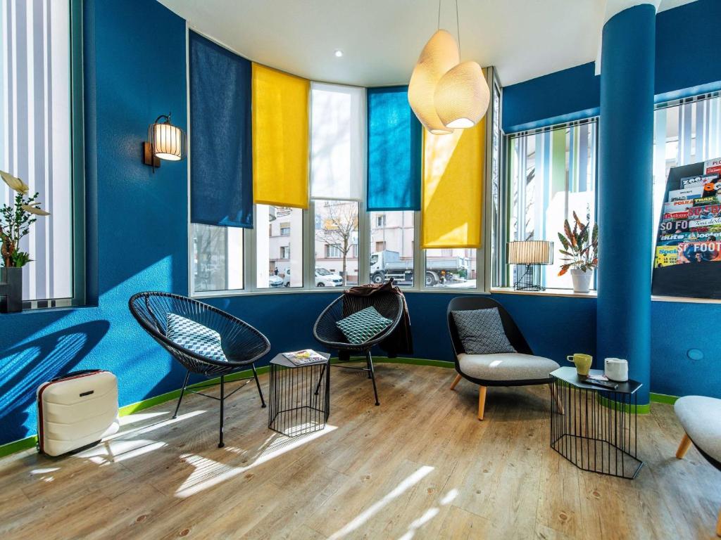 een kamer met stoelen en blauwe muren en ramen bij Ibis Styles Lyon Croix Rousse in Lyon