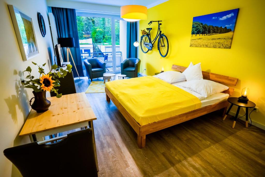 a yellow bedroom with a bed and a desk with a bike on the wall at Studio 13 "Rapsfeld" in Grömitz
