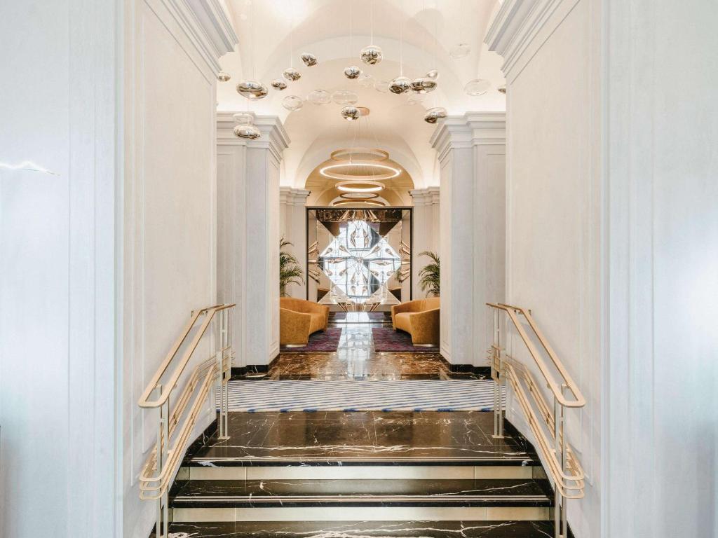 a staircase leading to a lobby with a chandelier at Raffles Europejski Warsaw in Warsaw