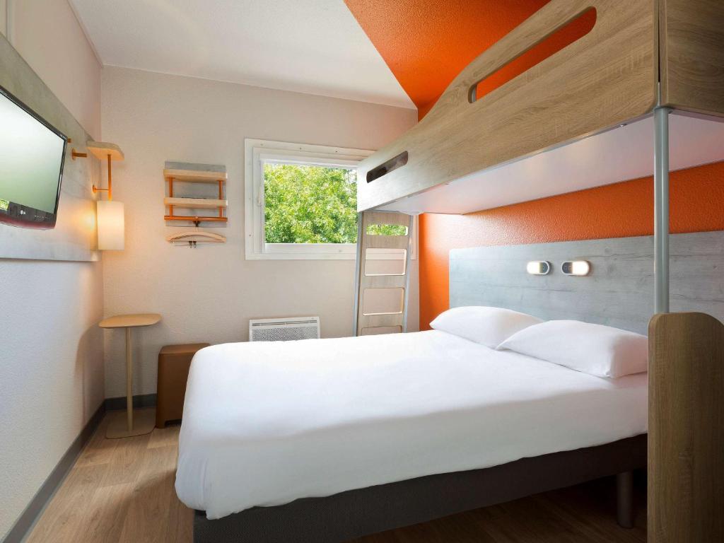 - une chambre avec un lit blanc et un mur orange dans l'établissement ibis budget Le Mans Universite, au Mans