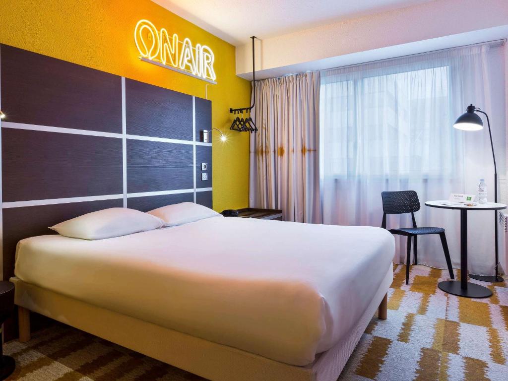 ein Hotelzimmer mit einem großen Bett und einem Tisch in der Unterkunft ibis Styles Massy Opéra in Massy