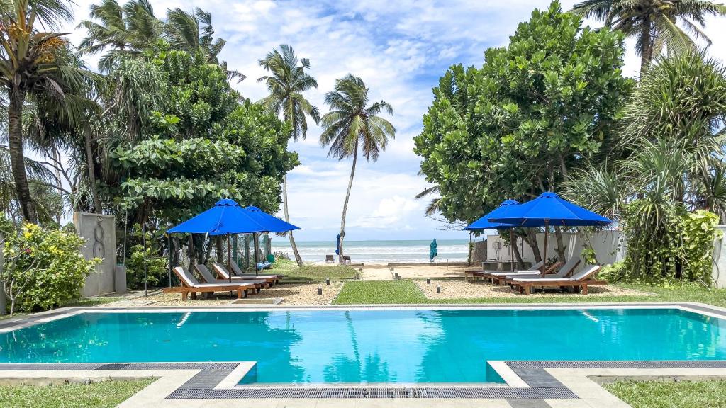 a swimming pool with chairs and umbrellas next to the beach at Parangi Weligama Bay - Thema Collection in Weligama