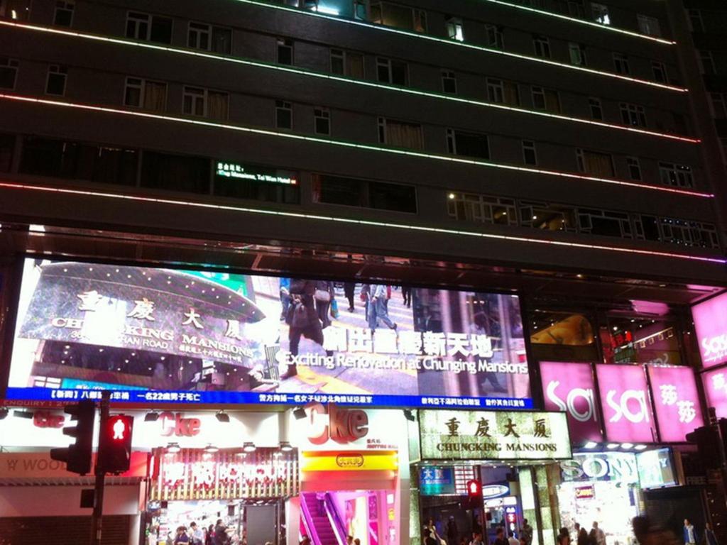 un gran cartel en una ciudad por la noche en C U Again Hostel, en Hong Kong