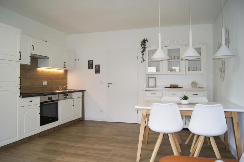 uma cozinha com armários brancos e uma mesa e cadeiras em Winterberg Appartement 21116 em Winterberg