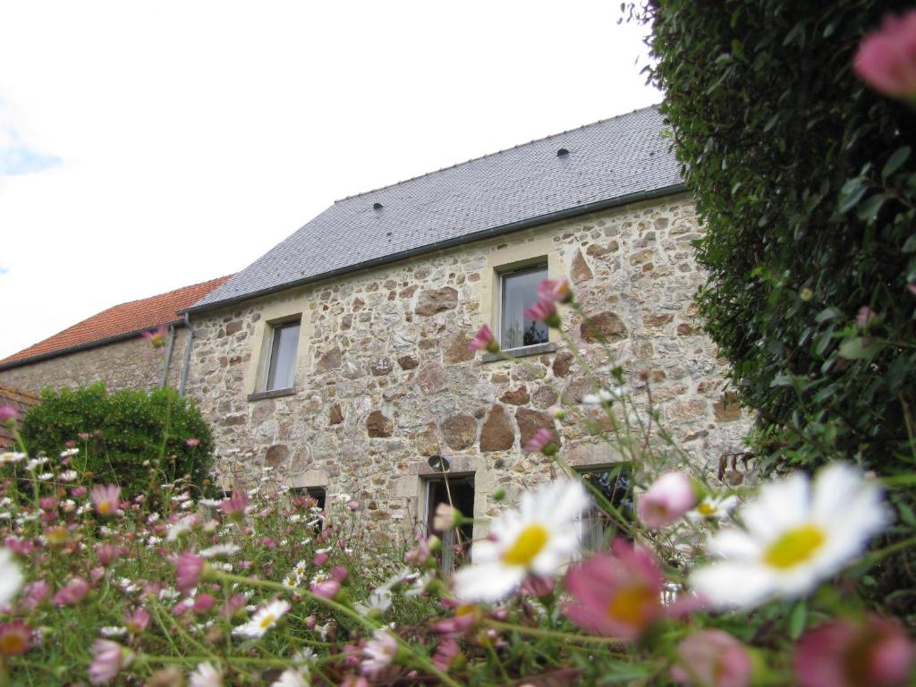 une maison en pierre avec des fleurs devant elle dans l'établissement Chambres d'hôtes de la Becterie, à Quettetot