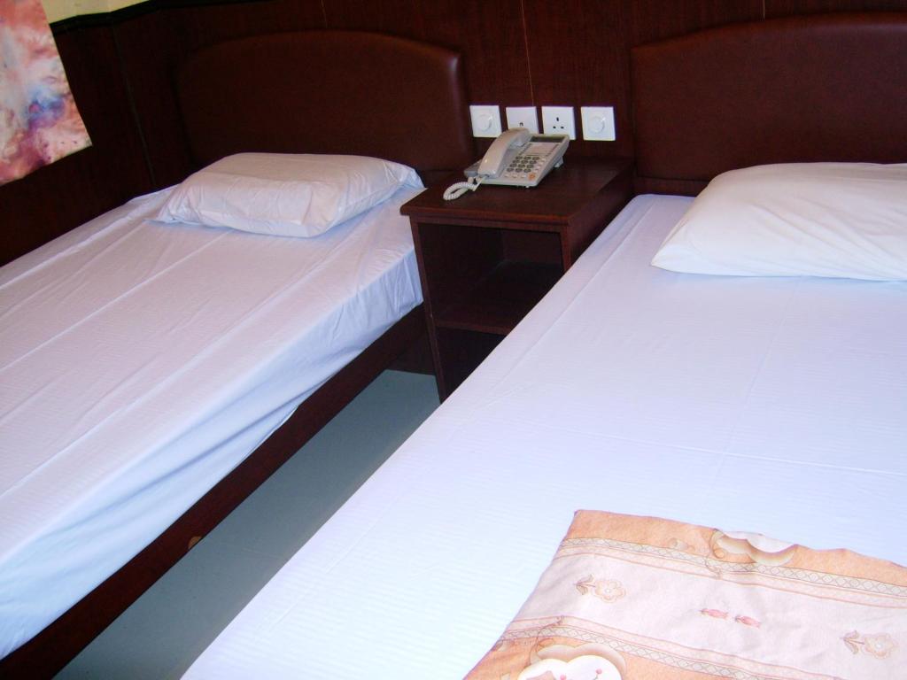 Dos camas en una habitación con un teléfono en una mesita de noche en Li’s Chain Hostel, en Hong Kong