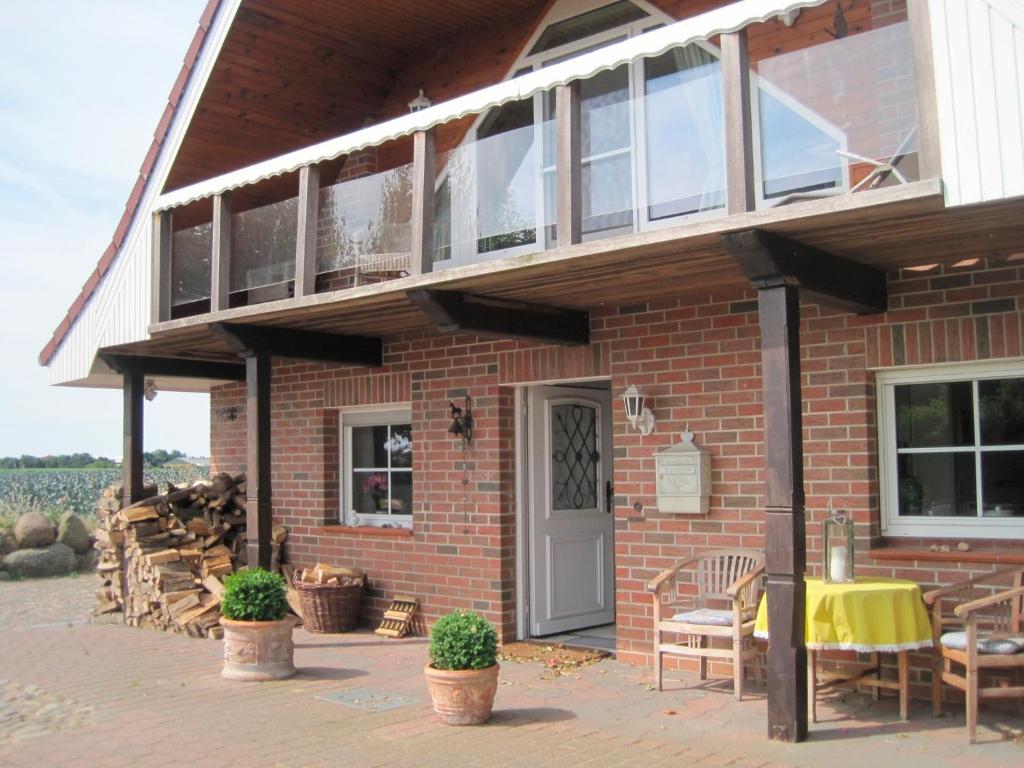 un edificio de ladrillo con porche, mesa y sillas en Ferienhaus Rüder "Schöne Aussicht", en Avendorf auf Fehmarn