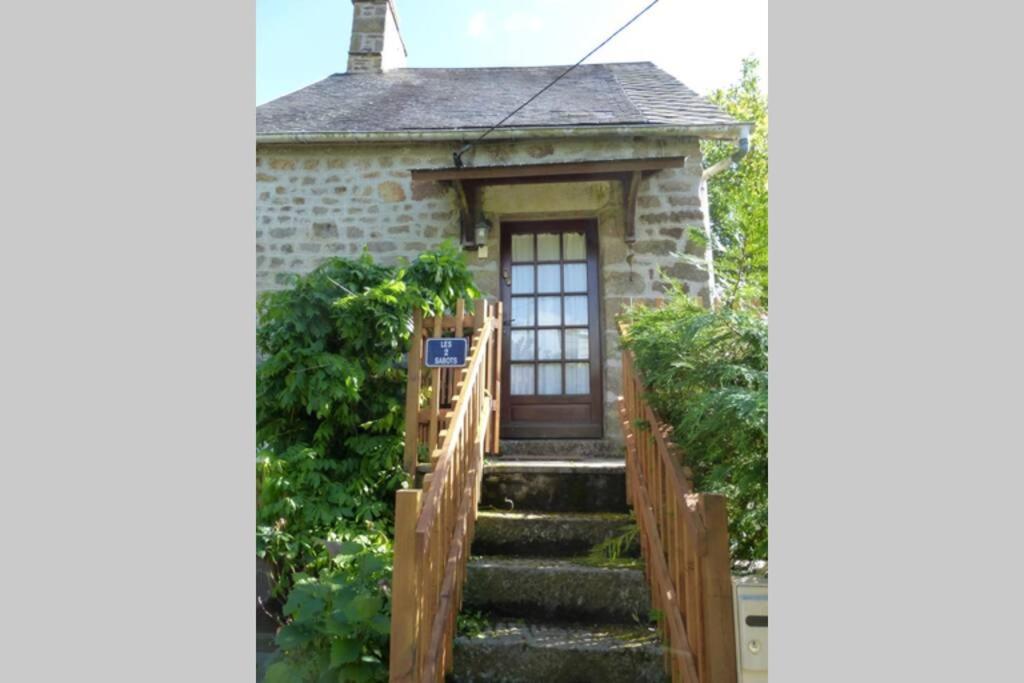 una pequeña casa de piedra con una puerta de madera y escaleras en Les Deux Sabots en Bréel