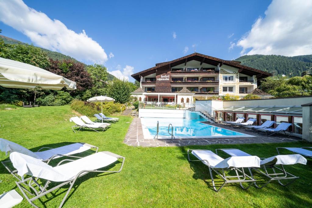 un complexe avec une piscine, des chaises et un bâtiment dans l'établissement Hotel Sonnalm, à Bad Kleinkirchheim