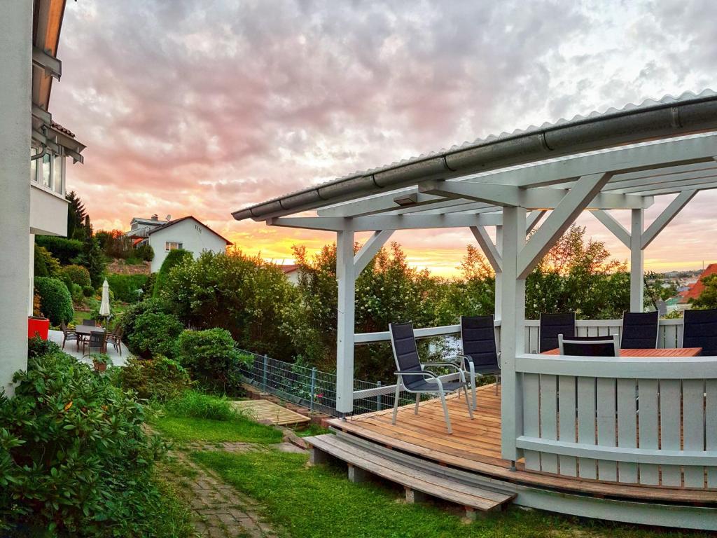 a deck with chairs and a pavilion with the sunset in the background at Villa - Ettenheim in Ettenheim