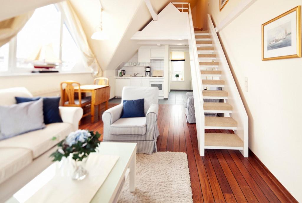 uma sala de estar com mobiliário branco e uma escadaria em Pirat em Laboe