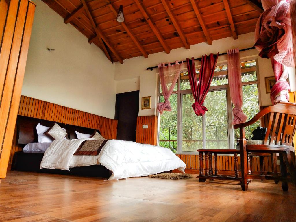a bedroom with a bed and a large window at The Canadian Woods Resort in Nainital
