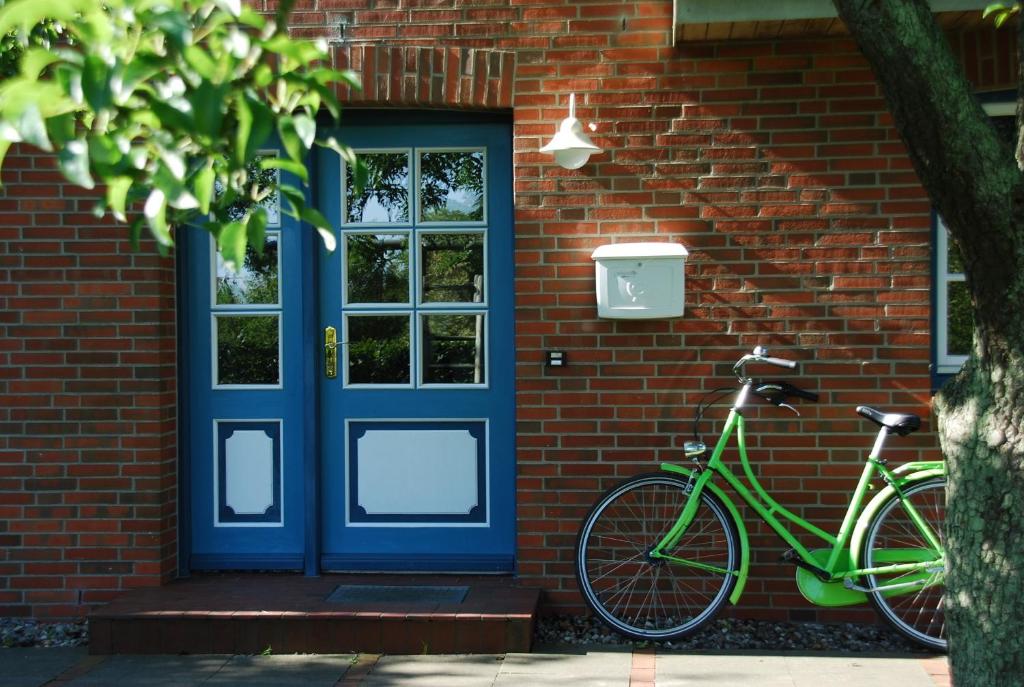 a green bike parked next to a brick house with a blue door at FöhrZeit in Wrixum