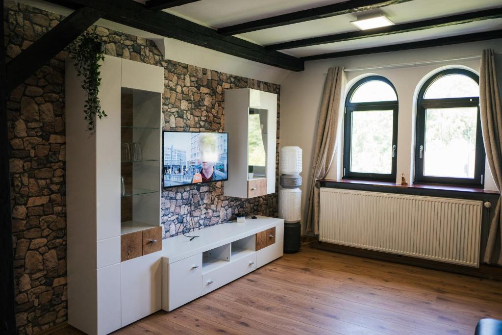 a living room with a tv and a stone wall at Alte Schule Spittelstein 1OG links - a22964 in Rödental