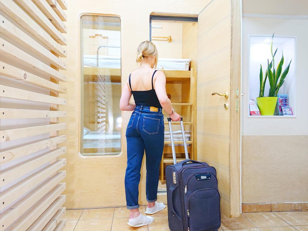 une femme debout avec une valise dans une pièce dans l'établissement AntiHostel Forrest, à Lviv