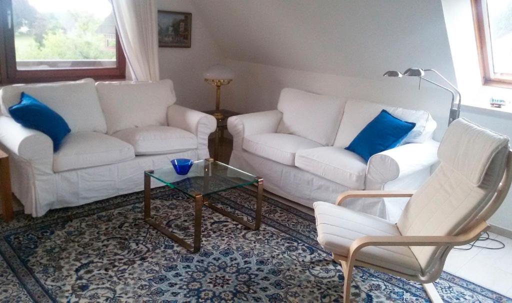 a living room with two white couches and blue pillows at Fewo Glücksburg in Ulsnis