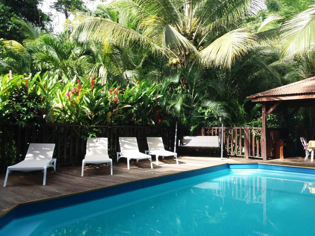 a pool with chairs and a gazebo and palm trees at Bungalow charmant à Pointe-Noire avec piscine partagée in Pointe-Noire