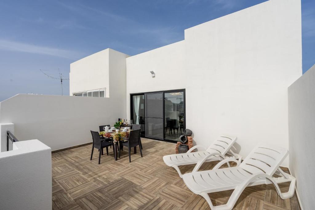 une salle à manger avec des chaises blanches et une table dans l'établissement Tulip Court Penthouse Brand New-2 Min From The Sea-Central Bugibba, à San Pawl il-Baħar
