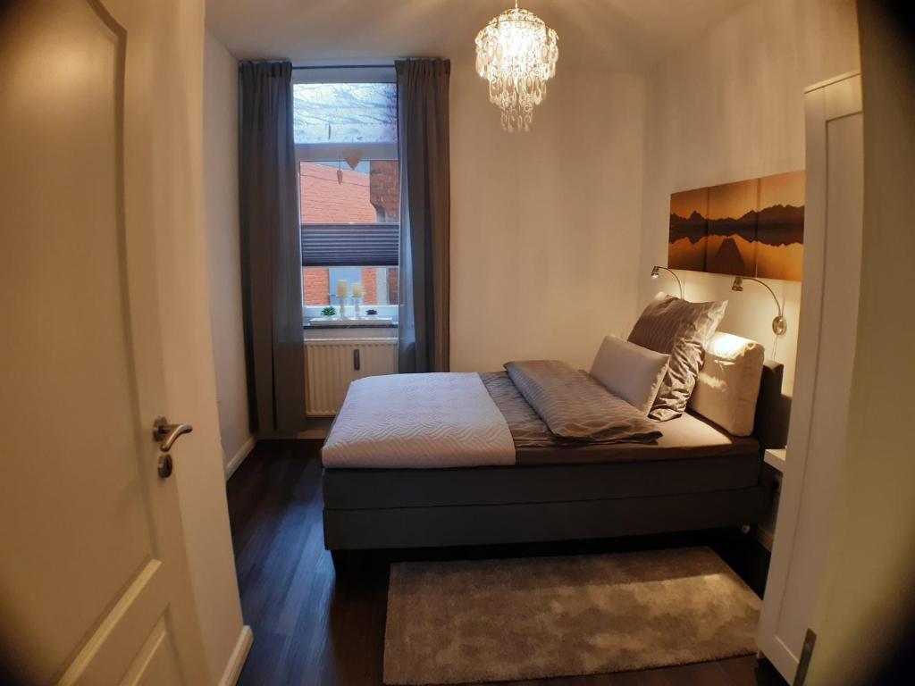 a bedroom with a bed with a chandelier and a window at Gleis acht in Bredstedt