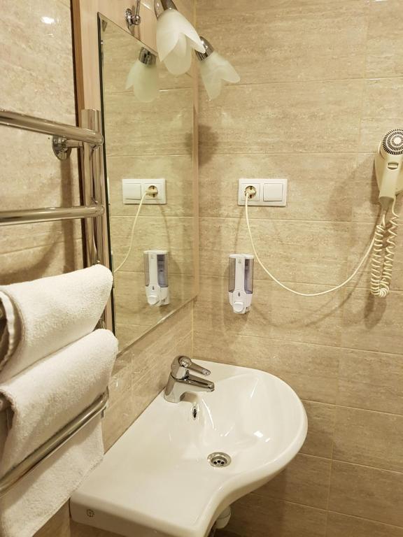 La salle de bains est pourvue d'un lavabo et d'un miroir. dans l'établissement Happy Inn Hotel Alpiyskiy, à Saint-Pétersbourg