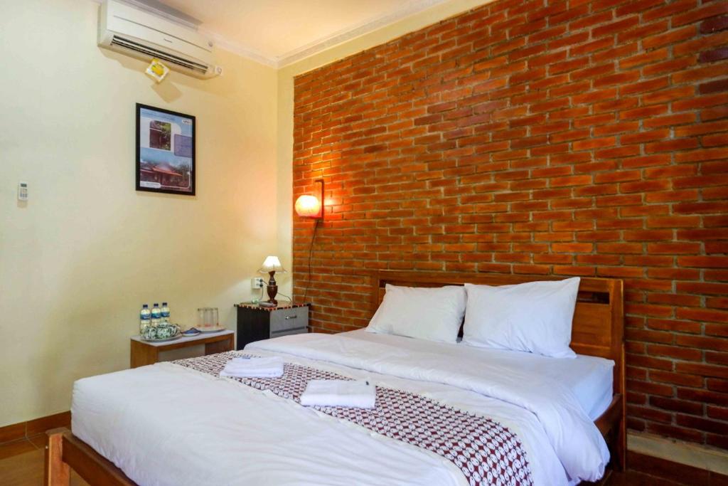 a bedroom with a brick wall and a bed at Roemah Beong Syariah at Desa Wisata Kembanglimus Mitra RedDoorz in Magelang