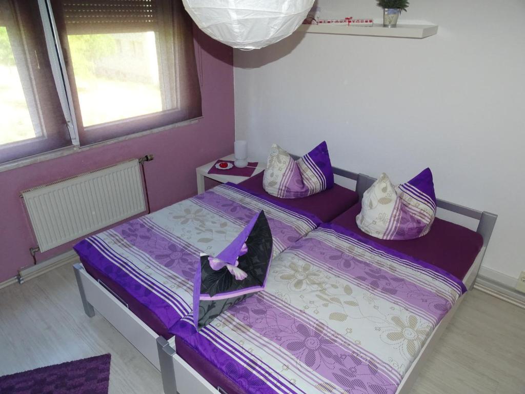ein lila Schlafzimmer mit 2 Betten und 2 Fenstern in der Unterkunft Ferienwohnung Kerstin in Wienrode