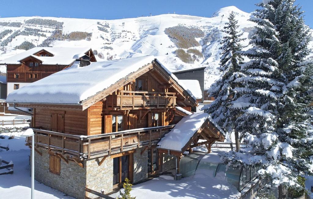 a log cabin in the snow with a snow covered mountain at Odalys Chalet Le Renard Lodge in Les Deux Alpes