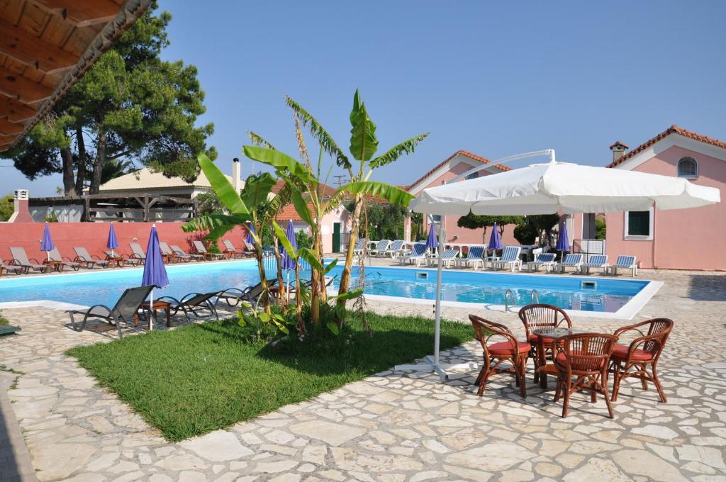 einen Pool mit Stühlen und Sonnenschirmen sowie einem Tisch und Stühlen in der Unterkunft Tassos Apartments in Acharavi