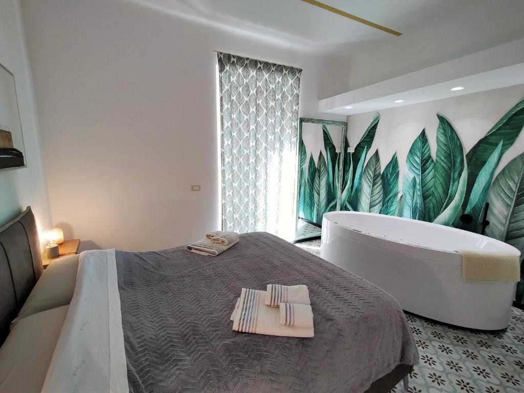 a bedroom with a bath tub and a bed with two towels at Sonnino Suite jacuzzi apartment in Bari