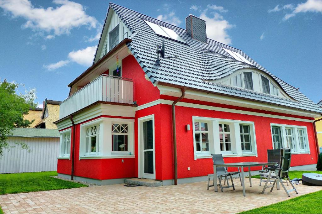 a red house with a table in front of it at Haus Windflüchter in Zingst