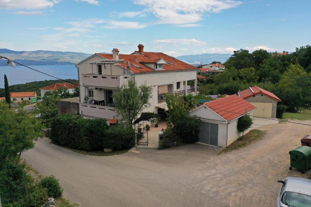 une grande maison blanche avec un toit rouge dans l'établissement Apartments House Risika, à Risika