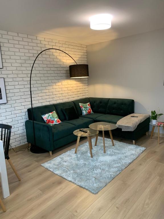 een woonkamer met een groene bank en een tafel bij Apartment Nadia in Ełk