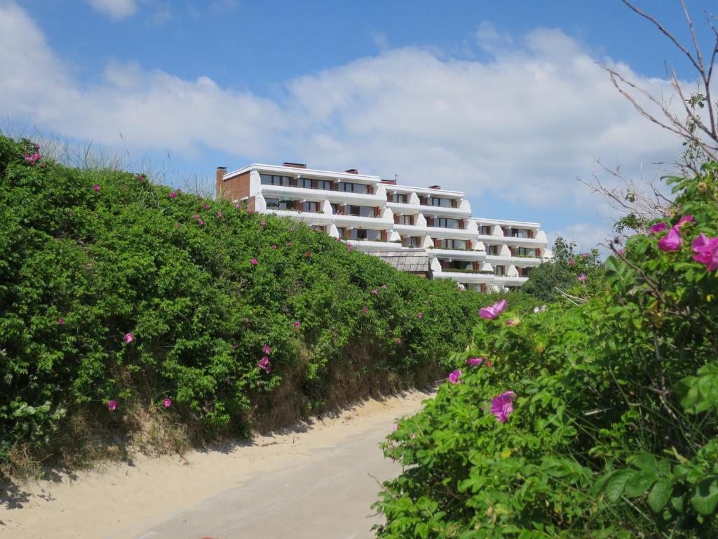 ein Gebäude auf einem Hügel mit Strand und Blumen in der Unterkunft Halligblick Whg 11 in Wyk auf Föhr