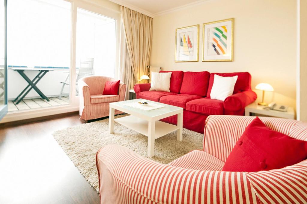 a living room with a red couch and a table at 470er Ferienwohnung in Laboe