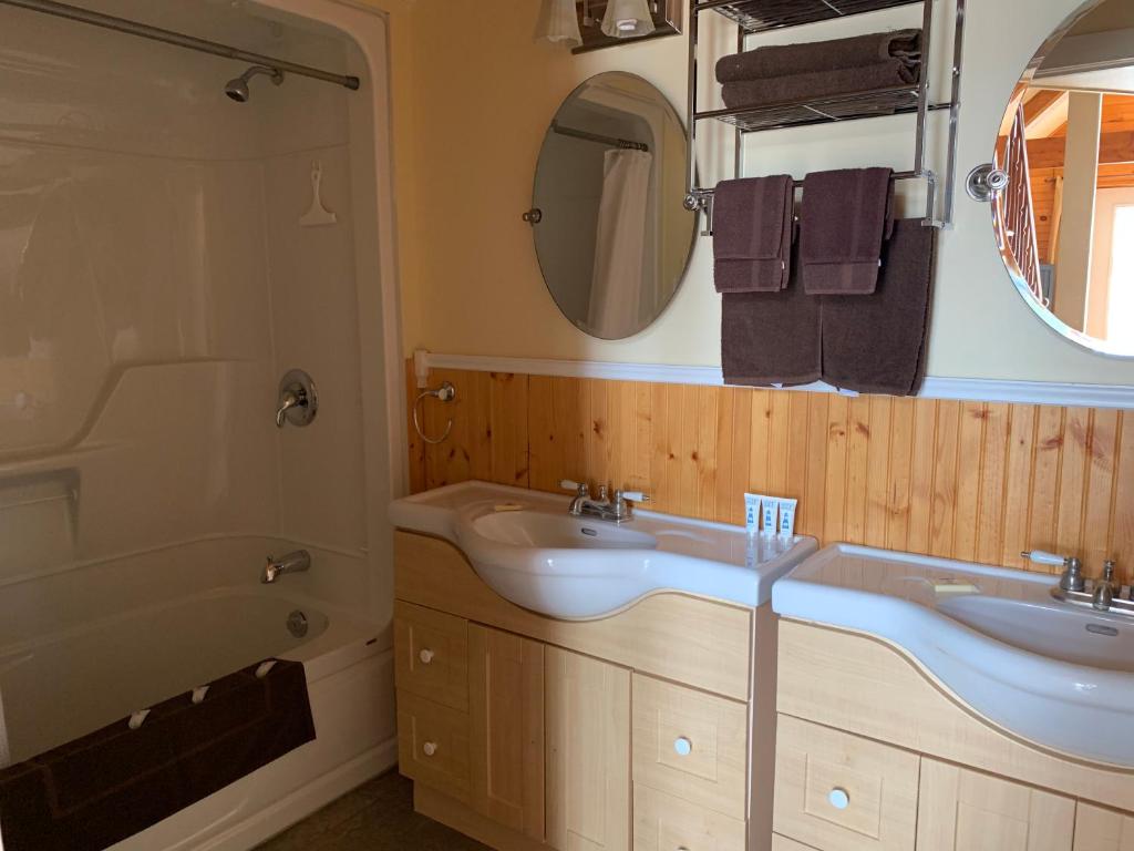 y baño con 2 lavabos, bañera y espejo. en Beach & Breeze Cottages, en Stanley Bridge
